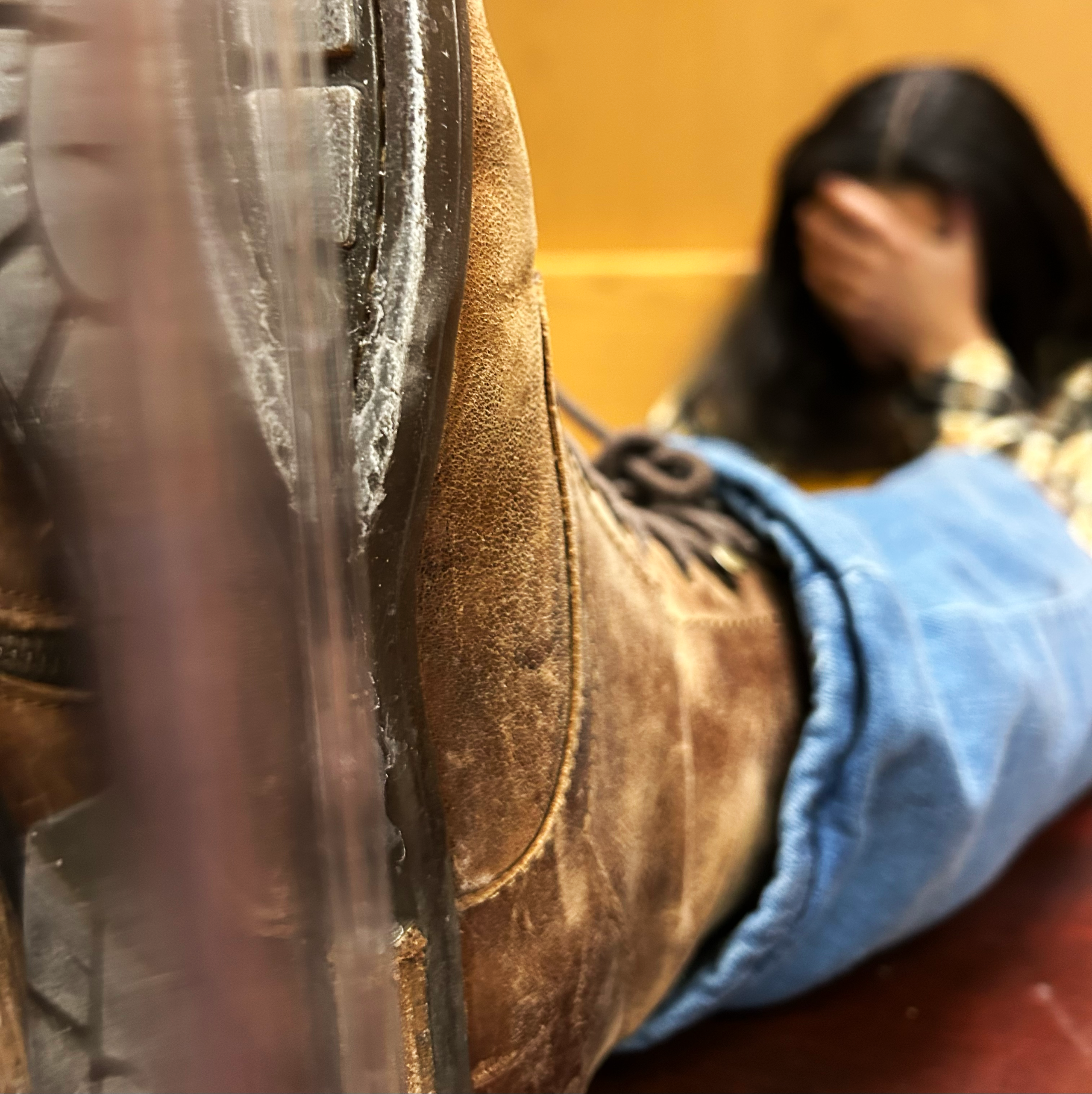 Girl sitting with her head in her hands and her leg extended. Her foot is reflected against a mirror.